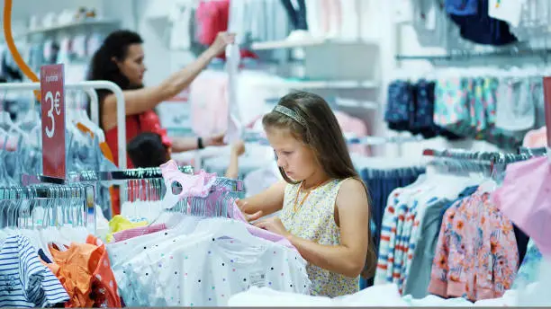 shopping in the store. children's clothing department. girl, kid, chooses things in the store. Little fashion-girl. little shopaholic. tedious shopping in stores, shops. High quality photo