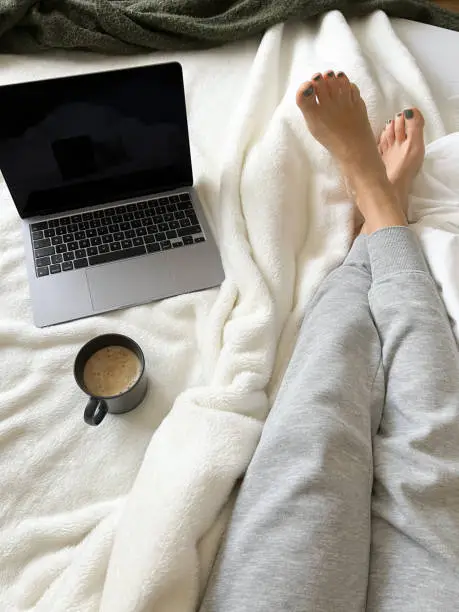 woman lying on bed in jogging pants in the morning writing blog post