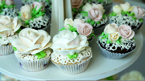 close-up, a variety of delicious desserts, cupcakes, cream cakes, whipped cream, flowers made with cream. festive decor, sweet bar, confectionery masterpieces, treats. High quality photo