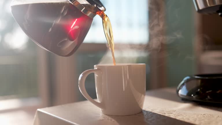 pouring fresh brewed coffee to the cup in the kitchen