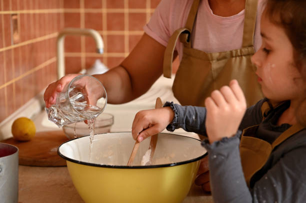 istock Selective focus on woman's hands pouring water into a bowl with white flour while kneading dough for festive cherry pie 1427301122