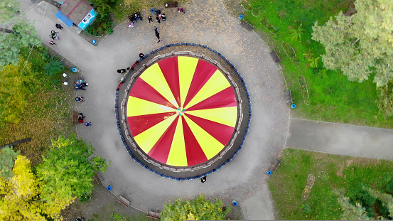 Colourful, red and yellow carousel, a carnival Merry Go Round, in the autumn park, aero, view from above. High quality photo