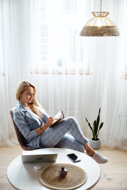 istock Young woman making notes in notebook sitting at workplace at home, remote work 1427308709