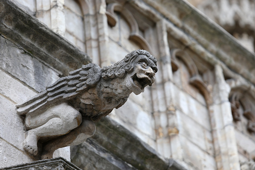 Monstrous statue with almost human features called gargoyle on the facade of the historic building