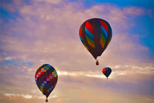 Multicolored hot air balloons ascend I the tranquil morning clouds