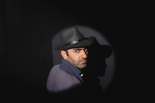 Portrait of a old man, in a cowboy hat with feather, with beard, front view - dark isolated silhouette