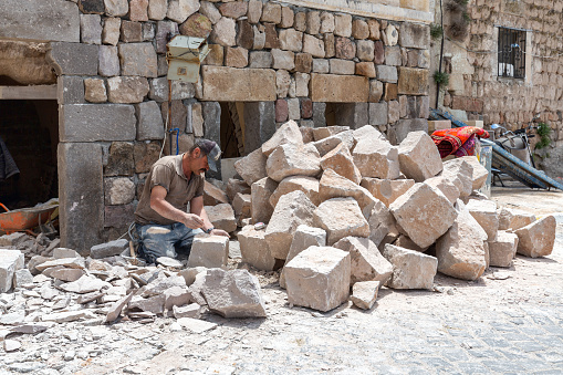 Uchisar, Cappadocia, Turkey - May 25, 2022: A stonemason is working stone to build a house in Uchisar