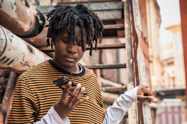 porträt eines jungen, gutaussehenden, stilvollen schwarzen mannes mit natürlichen haardreadlocks. afroamerikanischer typ. treppe, mit graffiti bemalte wand im armen viertel des stadtviertels street art culture. afroamerikaner skateboarder mann. millennia - graffiti men wall street art stock-fotos und bilder