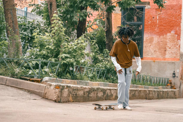 porträt eines jungen, gutaussehenden, stilvollen schwarzen mannes mit natürlichen haar-afro-dreadlocks. afroamerikanischer typ. treppe, mit graffiti bemalte wand im armen viertel des stadtviertels street art culture. afroamerikaner skateboarder mann. mil - graffiti men wall street art stock-fotos und bilder