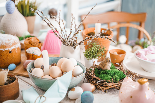 Table decoration for Easter celebration in kitchen.Tablescape for Easter holiday at home.Family religious traditional festive christianity,catholic meal food.Pop color eggs,cake,fun bunny,candy sweet.