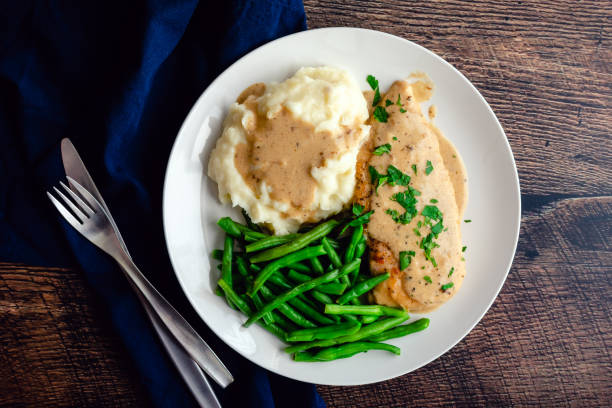 hähnchenbrust serviert mit grünen bohnen, kartoffelpüree und knoblauchsoße: hähnchenschnitzel mit cremiger knoblauchsauce serviert mit gemüse - feuerbohne stock-fotos und bilder