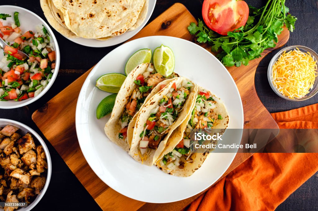 Chicken Tacos Topped with Pico de Gallo and Cheese Three tacos on a plate surrounded with toppings and tortillas Taco Stock Photo