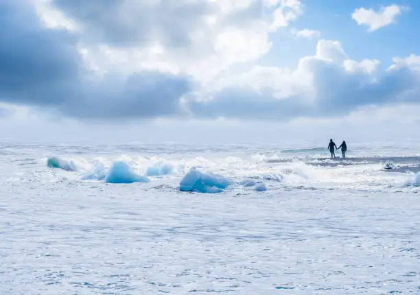 Photo of Large ice chunks from broken icebergs face the waves of the Atlantic ocean at diamond beach at the exit the JÃ¶kulsÃ¡rlÃ³n glacial lagoon in southeastern Iceland.