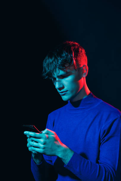 Studio portrait of a caucasian young man with a mobile phone on a black background stock photo