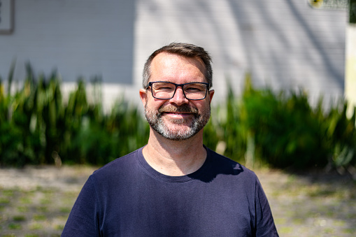 Portrait of a happy handsome mid adult man looking at camera and smiling outdoors on a sunny day