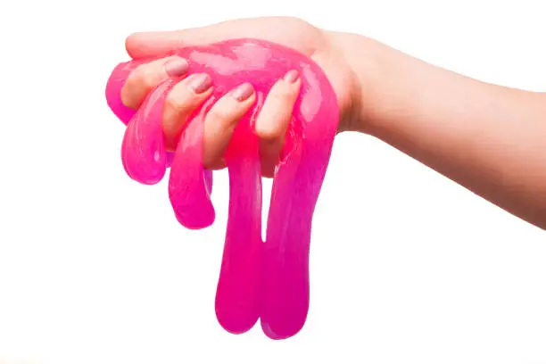 Photo of a toy for children mucus and liquid flowing on hand on a white background