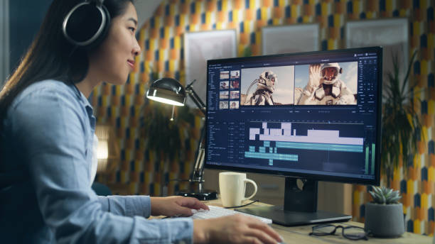 Female editor making video with astronauts Asian woman in headset editing video with astronauts for client in program on personal computer while working at the table from home office. Freelance female film editor stock pictures, royalty-free photos & images