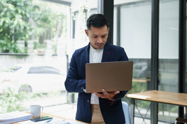 istock Portrait of an Asian male business owner standing using a computer to analyze work 1427367804
