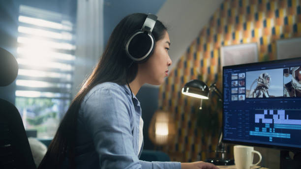 Female editor making video with astronauts Asian woman in headset editing video with astronauts for client in program on personal computer while working at the table from home office. Freelance female film editor stock pictures, royalty-free photos & images