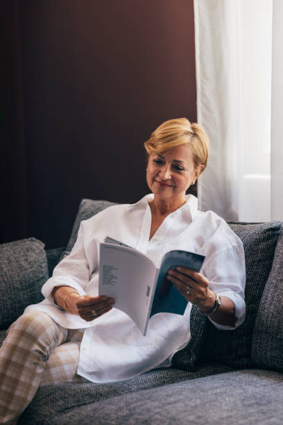 istock A Happy Beautiful Senior Woman Holding  Some Magazine While Rela 1427370015