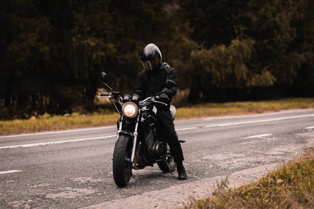 istock motorcyclist in a motorcycle jacket and a helmet with a sun visor on a custom motorcycle cafe racer. Stylish motorcyclist and autumn road. 1427370016