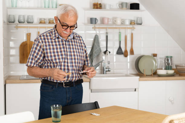 istock Senior man taking pills at home 1427376318