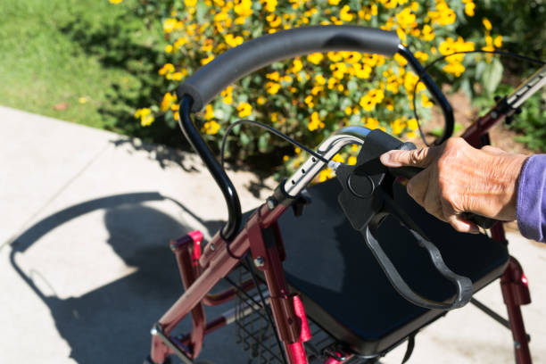 Elderly senior woman's hand on her mobility walker getting exercise at the park