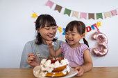 彼女の母親と自家製ケーキを食べる幸せな小さな女の子 - 歯の笑顔