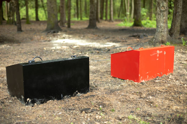 Two boxes in woods. Storage for sand. Safety equipment for firefighting. Red box and black.