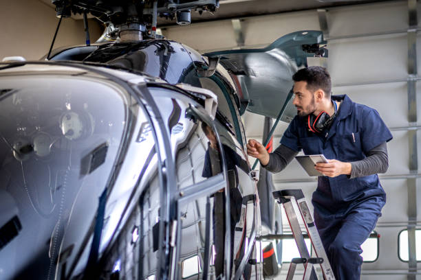 istock Aero mechanic in uniform standing on ladder and looking into jet, front side view 1427393980