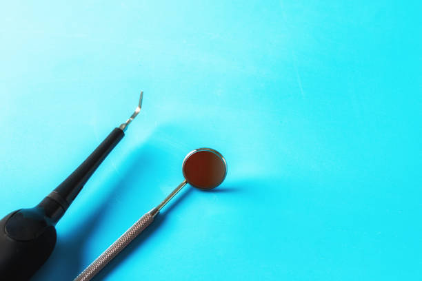 Dantist Month  mirror  and periodontal probe on blue background with copy space