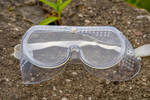 Goggles or safety glasses on the asphalt. Protective workwear to protect human eyes