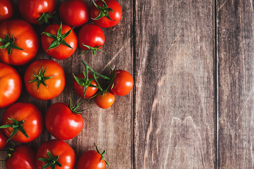 Tomatoes on wooden background, freshly picked red tomato fruit frame, cooking background, copy space