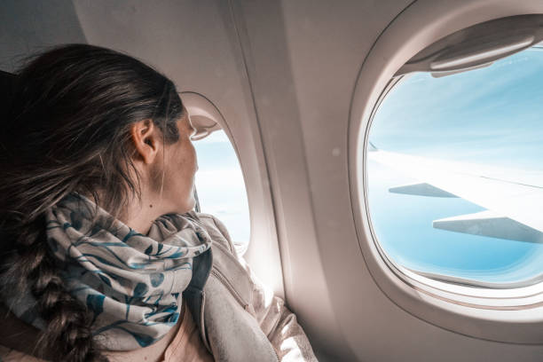 istock Woman flying in airplane, looking through window. Going on vacation. 1427410588