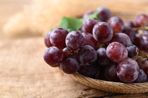 Red grape in basket on wooden background, Healthy fruit