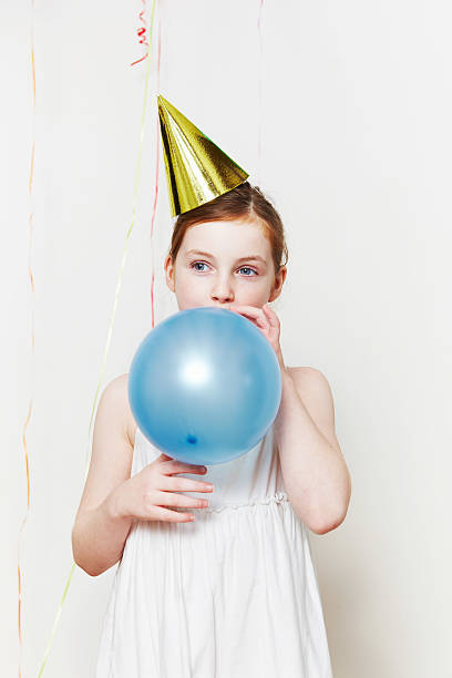 chica en gorro de fiesta con globos aerostáticos, soplando - balloon blowing inflating child fotografías e imágenes de stock