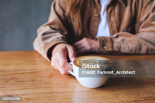 istock Closeup image of a woman holding coffee cup on wooden table 1427442190