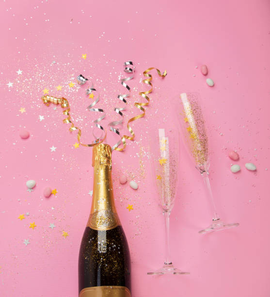 istock Champagne bottle with confetti on pink background. 1427443799