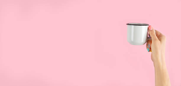 istock Arms raised up holding coffee cup on pink background. 1427443890