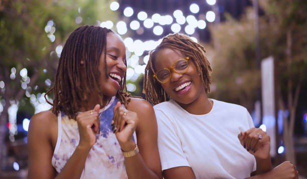 Black twin sisters enjoying a moment of fun in a park at night stock photo