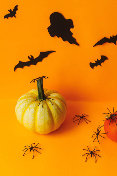 istock Happy Halloween! Black spiders on pumpkin and ghosts, bats decorations on orange background. Modern Halloween still life. Card template with space for text 1427446033