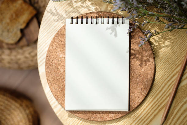 mockup blank sprial notebook top view on wood table with morning sunlight