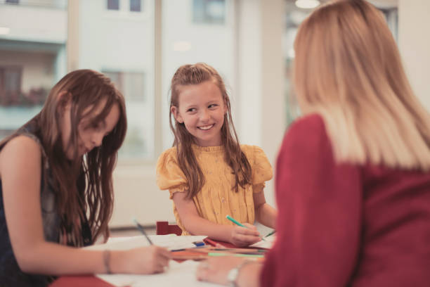 istock Creative kids during an art class in a daycare center or elementary school classroom drawing with female teacher. 1427451849