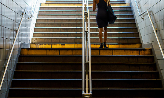 Pedestrian woman walking on staircase, low angle view. New York, USA