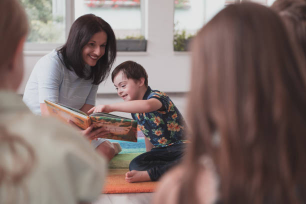 Reading time in an elementary school or kindergarten, a teacher reads a book to children in an elementary school or kindergarten. The concept of pre-school education. Selective focus Reading time in an elementary school or kindergarten, a teacher reads a book to children in an elementary school or kindergarten. The concept of pre-school education. Selective focus. special education stock pictures, royalty-free photos & images