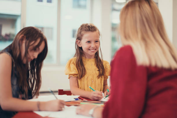 istock Creative kids during an art class in a daycare center or elementary school classroom drawing with female teacher. 1427457184