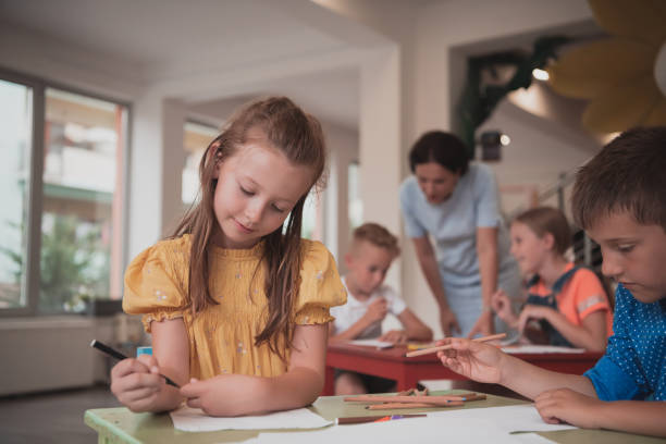 istock Creative kids during an art class in a daycare center or elementary school classroom drawing with female teacher. 1427457515