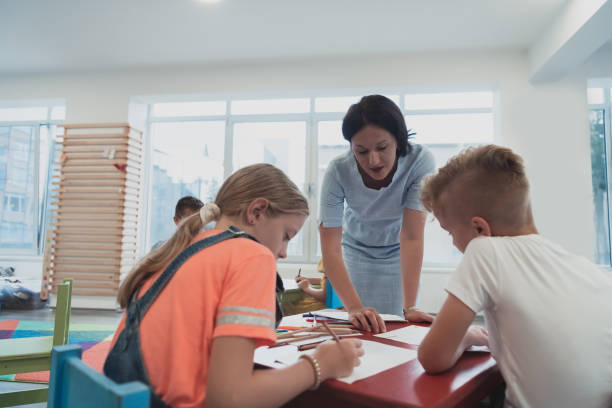 istock Creative kids during an art class in a daycare center or elementary school classroom drawing with female teacher. 1427459192