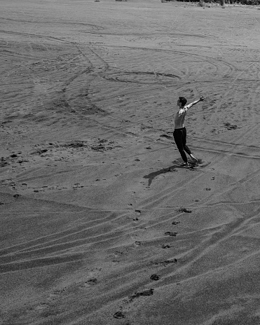 Young man walking alone on the sand in sandy desert. Black and white