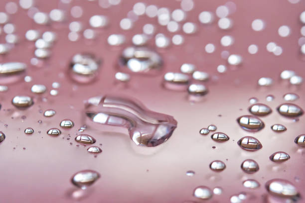 istock A large drop and splashes of micellar water on a pink background. 1427464419